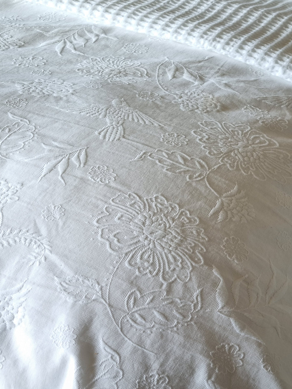 Close-up of textured white fabric with floral patterns